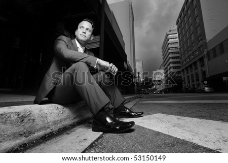 Businessman sitting on a curb in the city