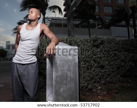 Handsome black man posing by a pay-phone