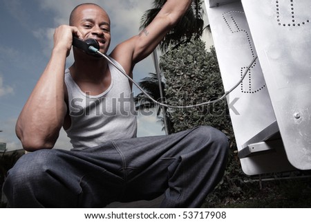 Image of a man squatting and talking on a pay phone