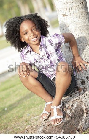 Young African American child sitting on a tree