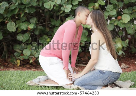 Two young women kissing in the park