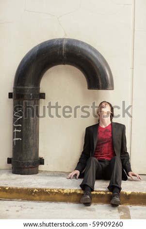 Man sitting under a metal pipe and looking inside