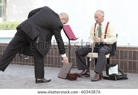 Businessman giving money to the clarinet player
