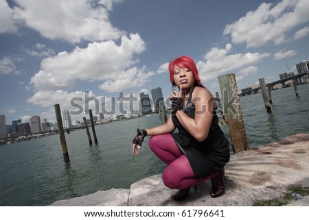 Young fashionable woman squatting by the docks