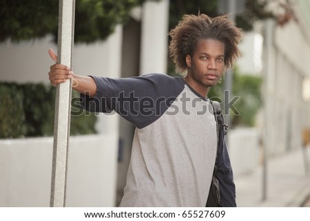 Young black man holding on to a street sign