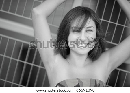 Black and white image of a woman with arms grabbing on to the abstract metal background