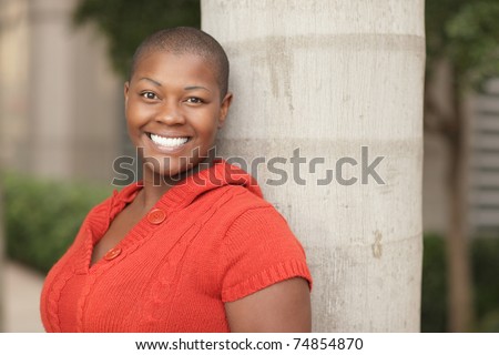 Young black woman leaning on a tree
