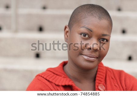 Headshot of a young black woman with a shaved head