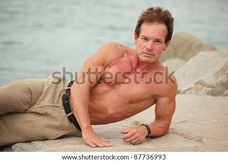 Body builder posing on the rocks
