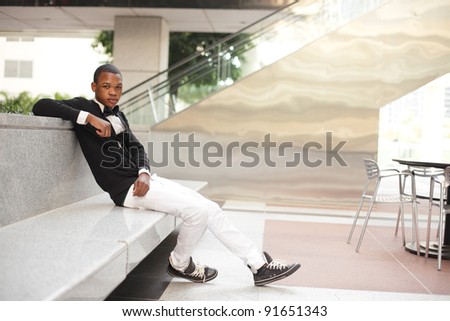 Young fashionable black model sitting on a concrete bench