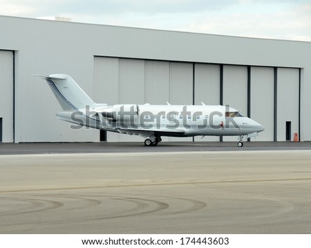 Modern corporate jet airplane in front of hangar