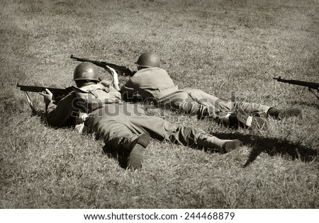 Two World War 2 era soldiers on the ground shooting