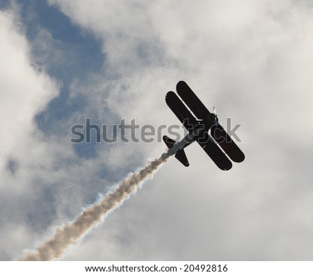 Vintage biplane performing an aerial stunt with smoke