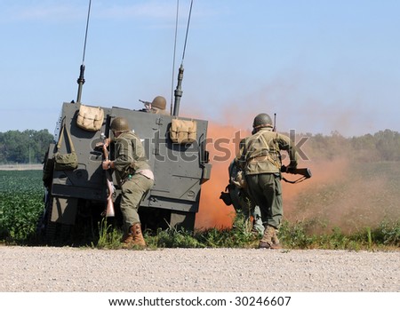 Soldiers engaged in gun battle behind armored vehicle