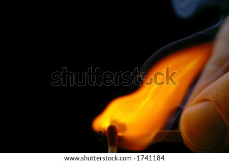 Closeup of a red-tipped wooden match stick at ignition from another match being held by fingers.  Red, orange, yellow, and white flame.  Black background.