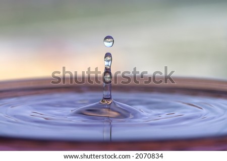 Closeup of a water droplet splashing into a water pool.  City skyline is visible in the uppermost water droplet.