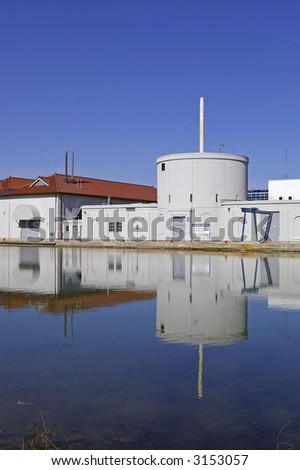 A portion of an urban (potable) Water Treatment Plant against a blue sky background.  Building reflection is visible in water.  Toronto Island facility, Toronto, Ontario, Canada.