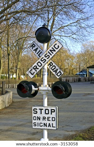 A miniature Railway Crossing sign with lights and bell with \'Stop on Red Signal\' sign.  Miniature (park-sized) sign in Centre Island park, Toronto, Ontario, Canada.