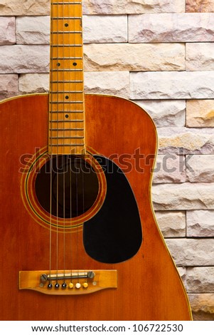 close up vintage acoustic guitar on sand stone wall