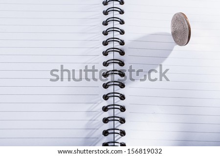 Coin on empty notebook on isolated white background