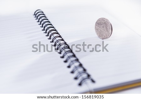 Coin on empty notebook on isolated white background