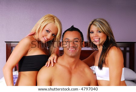 Hispanic man with two women on bed in bedroom