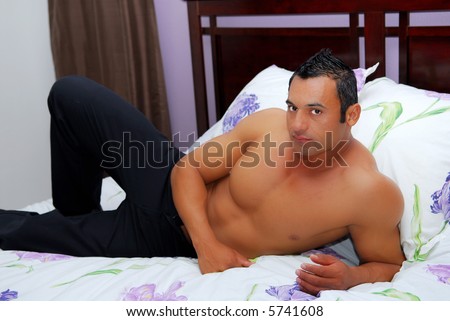 Handsome muscular hispanic male model lying on bed