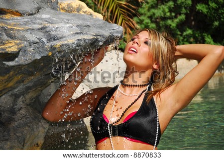 Beautiful blond glamor model in black bikini in pool
