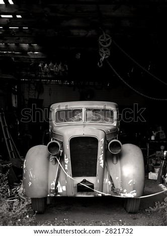 A vintage car photographed in black and white awaits the opportunity to run again