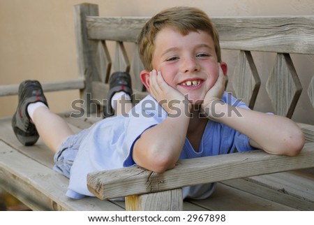 A young boy stretches out on a big chair and smiles