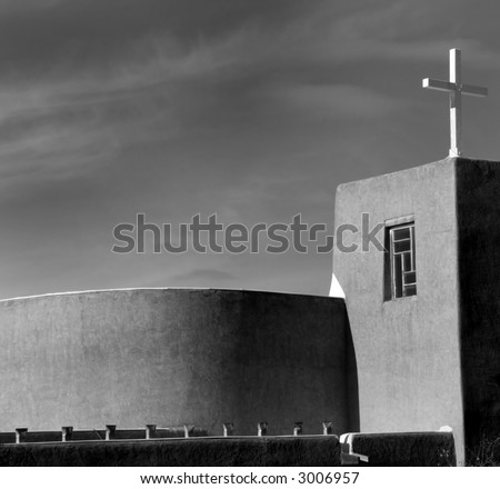 A small wooden cross on a modern church in black and white