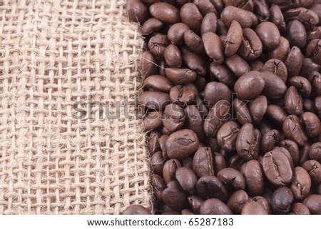 close up of dark roasted fair trade coffee beans on jute covering half of the picture