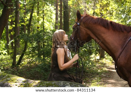 Beautiful young girl in brown dress and chestnut horse at the forest