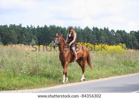 Beautiful young teenager girl in brown dress and chestnut horse walking on the road
