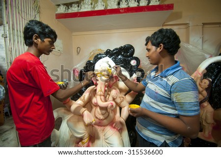 MUMBAI, MAHARASHTRA - 28th  AUGUST 2014 : artist gives finishing touches on an idol of the Hindu god Lord Ganesha at an artist\'s workshop for Ganesha-festival, 28th August 2014, Maharashtra, India.