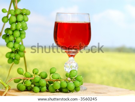 fresh grapes (selected focus) and a red glass of wine in background