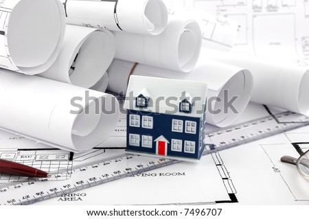 home plans and ruler pen and a miniature house