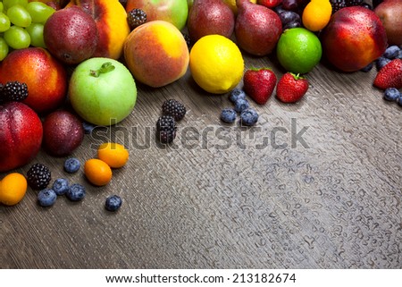 Border of mixed fruits with water drops on beautiful wooden texture - copy space