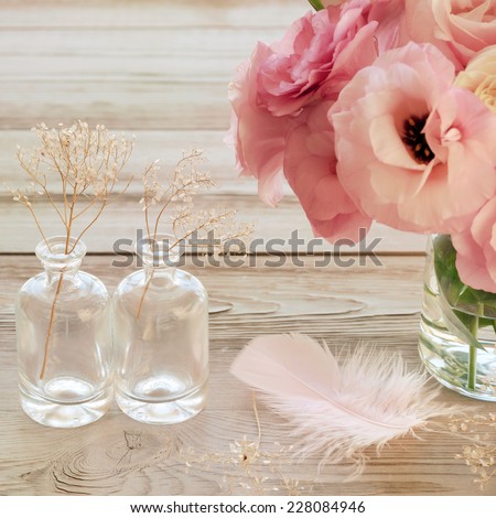 Still life with pink flowers in a vase with feather and two glass botles - vintage look