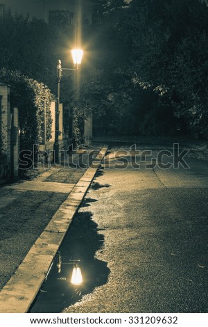 Night scene after rain - lantern lights and puddle, old street in the town, vintage toned