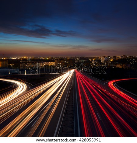 Speed Traffic at night  in the city - light trails on motorway highway at dusk,  long exposure, urban background with illumination