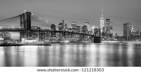 Panoramic view of  Brooklyn Bridge and Lower Manhattan skyline in New York City at night with city illumination, USA. Black and white toned
