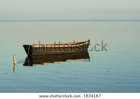 Lonely boat in the quiet sea sundawn. Water iron also reflection