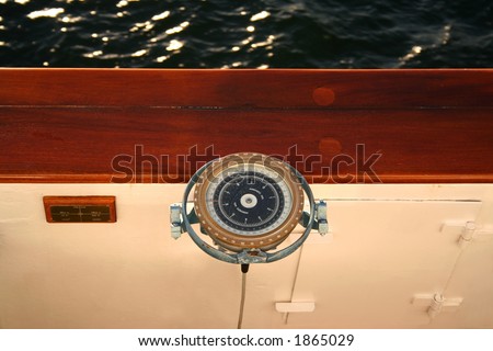 Modern compass onboard of the liner. Little bit shabby but beautiful. A close up. A geometrical composition. Behind a board of a wave in beams the sun.