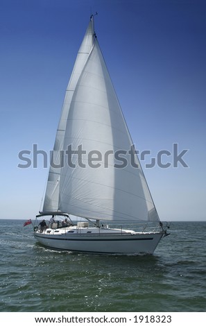 The large beautiful yacht with white sails on a background of the brightly light-blue clean sky and quiet sea.