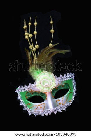 Vintage green and silver dress mask with feathers and flower isolated on a black background