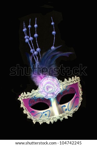 Vintage purple / pink and silver dress mask with feathers and flower isolated on a black background