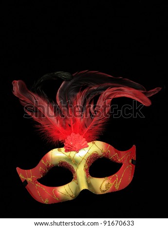 Fancy Red and Gold Feathered Mask isolated on a black velvet background