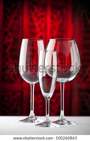 Red, white and champagne wine glasses standing on a table with beautiful dark red background