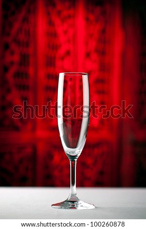 Champagne glass standing on a table with beautiful dark red background
